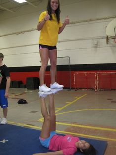 a woman in yellow shirt and shorts standing on top of a blue mat with pink shoes