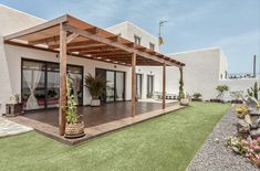 an outdoor patio with wooden pergols and potted plants on the grass area