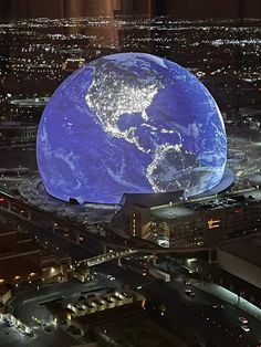 an aerial view of the earth at night with city lights and buildings in the background