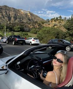 a woman sitting in the driver's seat of a convertible car