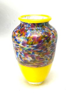 a colorful vase sitting on top of a white table next to a yellow cup holder