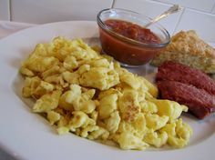 a white plate topped with macaroni and cheese next to a bowl of tomato sauce