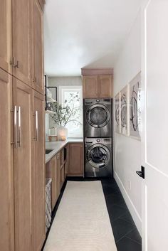 a washer and dryer in a small room with wood cabinets on either side