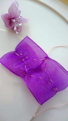 a purple piece of cloth with some thread on it and a flower in the middle