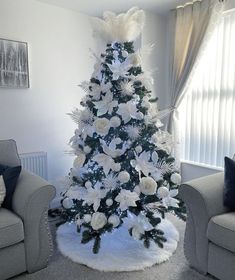 a white christmas tree decorated with flowers and feathers