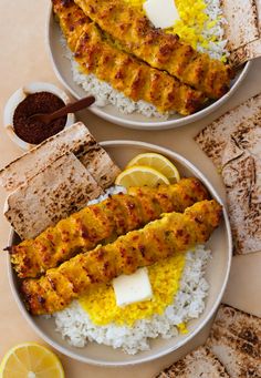 two plates filled with different types of food on top of rice and pita bread