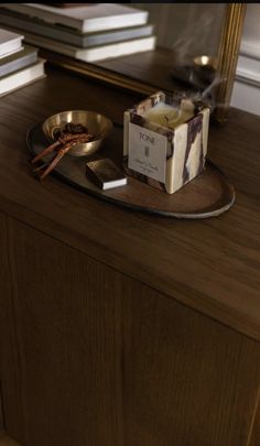 a wooden table topped with a bowl of food and a candle on top of it