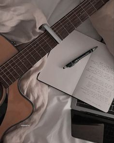 an open notepad sitting on top of a guitar