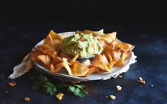 a plate filled with chips and guacamole on top of a blue table