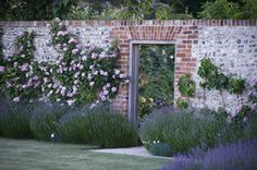 a brick wall with flowers and bushes surrounding it