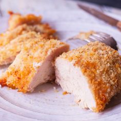 two pieces of chicken on a plate with a fork