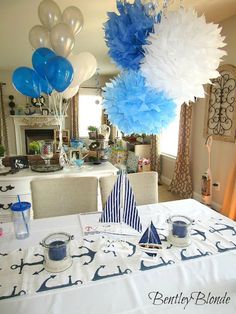 a table topped with blue and white balloons