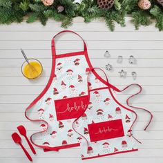 two aprons with personalized names on them next to pine cones and christmas decorations