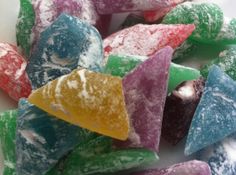 colorful candies sitting on top of each other in different colors and shapes, all covered with powdered sugar