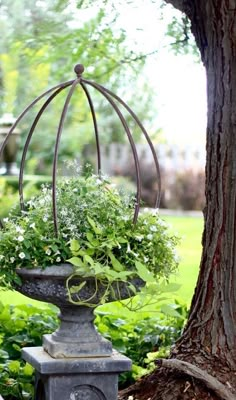 a potted planter with flowers in it sitting on a stand next to a tree