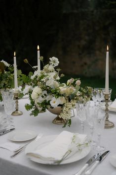 the table is set with white flowers and candles