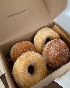 four donuts in a box with sugar sprinkled on them