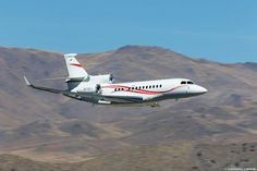 an airplane is flying in the sky over some hills and mountains with a mountain range behind it