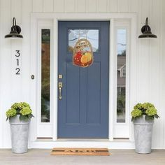 two potted plants are on the front step of a house with a blue door