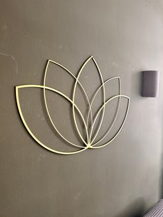 a metal wall sculpture on the side of a gray wall next to a white bed