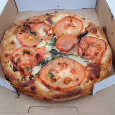 a pizza in a box with tomatoes on it