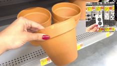 a woman holding up two clay pots with numbers on them in front of a store shelf