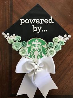 a starbucks cap with roses and flowers on it that says powered by, is attached to a wooden table