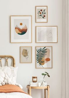 a bedroom with white walls and pictures on the wall above the bed, along with a wicker side table