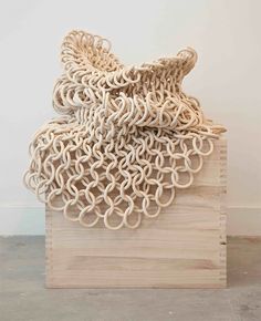 a sculpture made out of woven material sitting on top of a wooden block