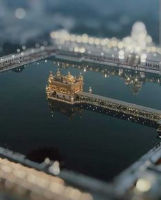 an aerial view of a building in the middle of water with lights all around it