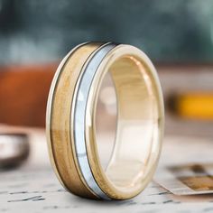 two tone gold and silver wedding band ring on top of a piece of paper next to a calculator