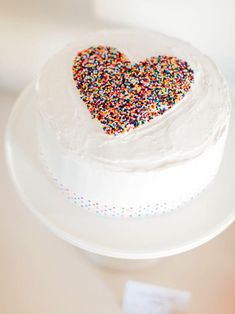 a white cake with sprinkles in the shape of a heart on a plate