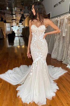 a woman in a wedding dress standing on a wooden floor