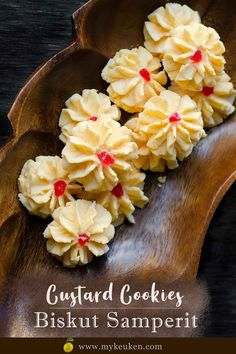 some cookies are on a wooden plate with the words, custard cookies biscuit samperi