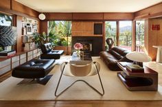 a living room with couches, chairs and a fire place in the middle of it