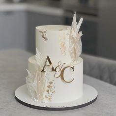 a white wedding cake with gold leaves and initials