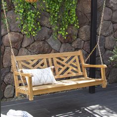 a wooden bench sitting on top of a porch next to a stone wall and green plants