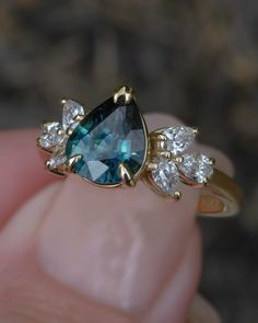 a blue and white diamond ring sitting on top of someone's finger