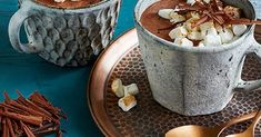 two cups filled with hot chocolate and marshmallows on top of a plate