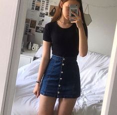 a woman taking a selfie while wearing a denim skirt and black t - shirt