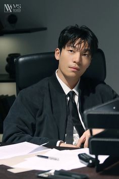 a young man sitting at a desk in front of a laptop computer