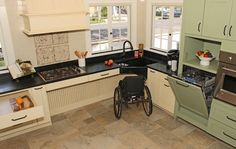 a wheelchair is in the middle of a kitchen with black counter tops and white cabinets