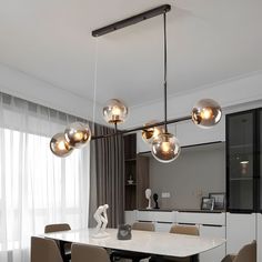 a dining room table with chairs and lights hanging from it's ceiling over it