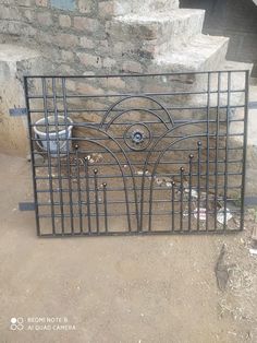 an iron gate in front of a brick wall and steps with trash cans on the ground