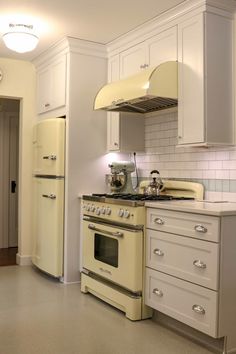 an old fashioned stove and oven in a kitchen with white cupboards, cabinets and drawers