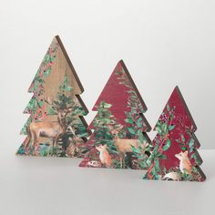 three wooden christmas trees with deers and pine cones on them, all decorated in different colors