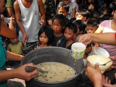 a group of people are gathered around a large pot filled with soup and ice cream