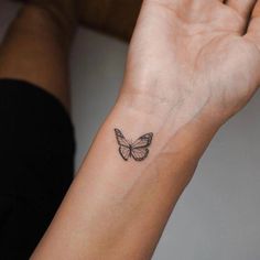 a woman's wrist with a small butterfly tattoo on the left side of her arm