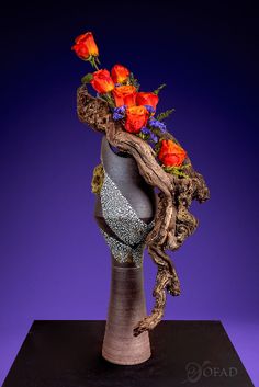 a vase with flowers in it sitting on a black stand against a purple background,