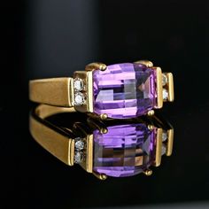 Chic vintage specialty barrel cut amethyst ring with diamond accents set in a sleek 10K yellow gold.  The rich purple amethyst is in a raised setting set above a wide gold band with channel-set diamonds on each side.  The gemstone is curved at the top and sides so that light dances off the faceting with movement.  Unique vintage ring for the February birthday lady or those that love purple! Materials: 10 karat gold Gemstone: Natural Amethyst - 10mm by 8mm; Diamonds - 2 points each Ring size: 6.7